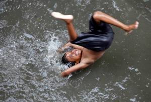 A boy plays on a flooded street during a monsoon rain in Kolkata
