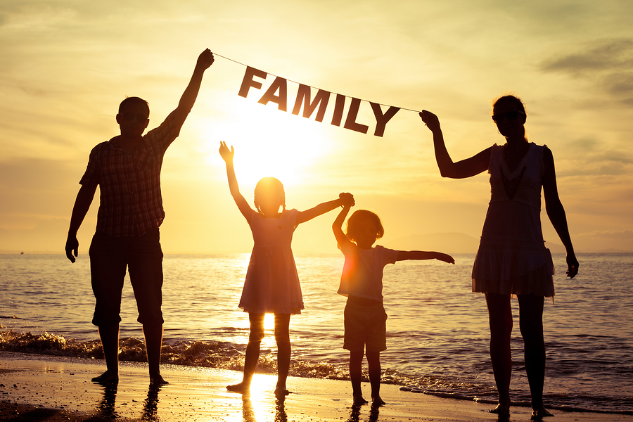 Happy Family Standing On The Beach